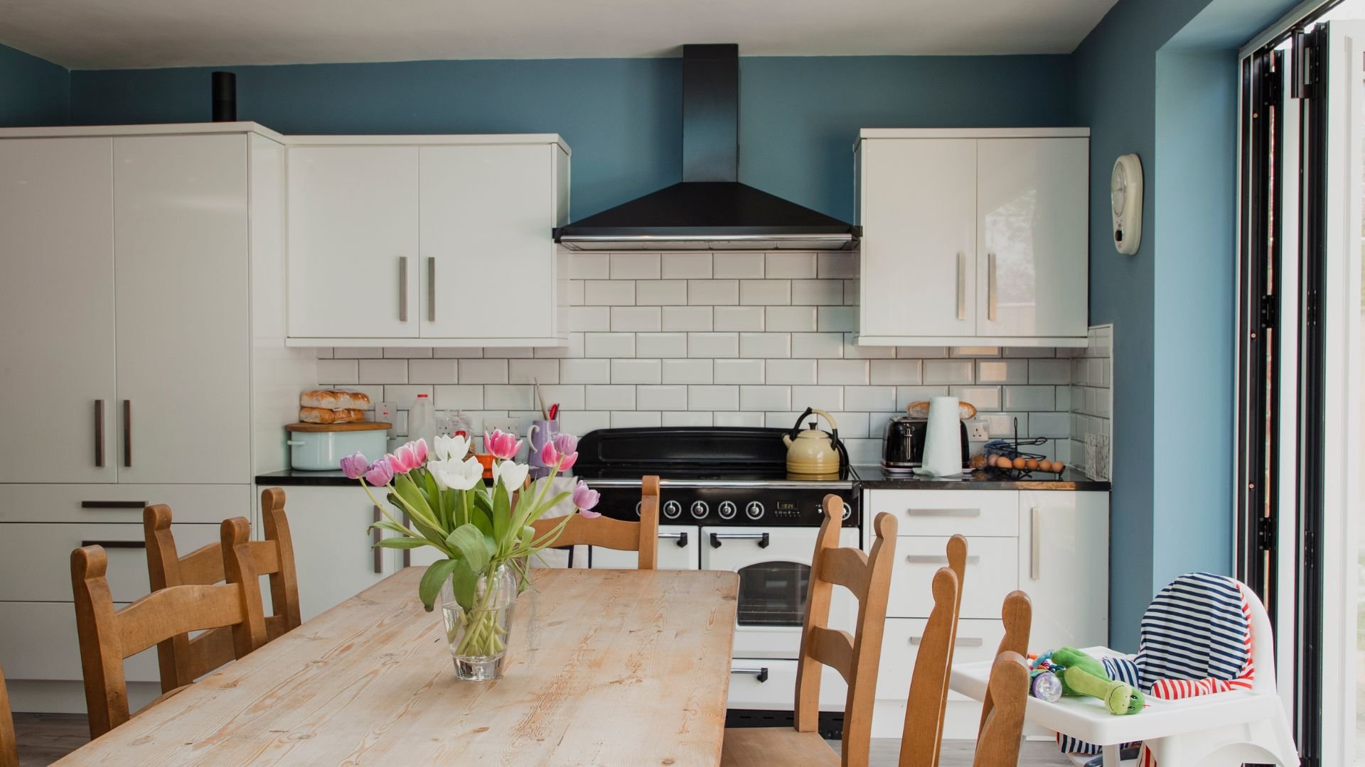 Modern kitchen with white cabinets, wooden table, tulips, and vintage stove