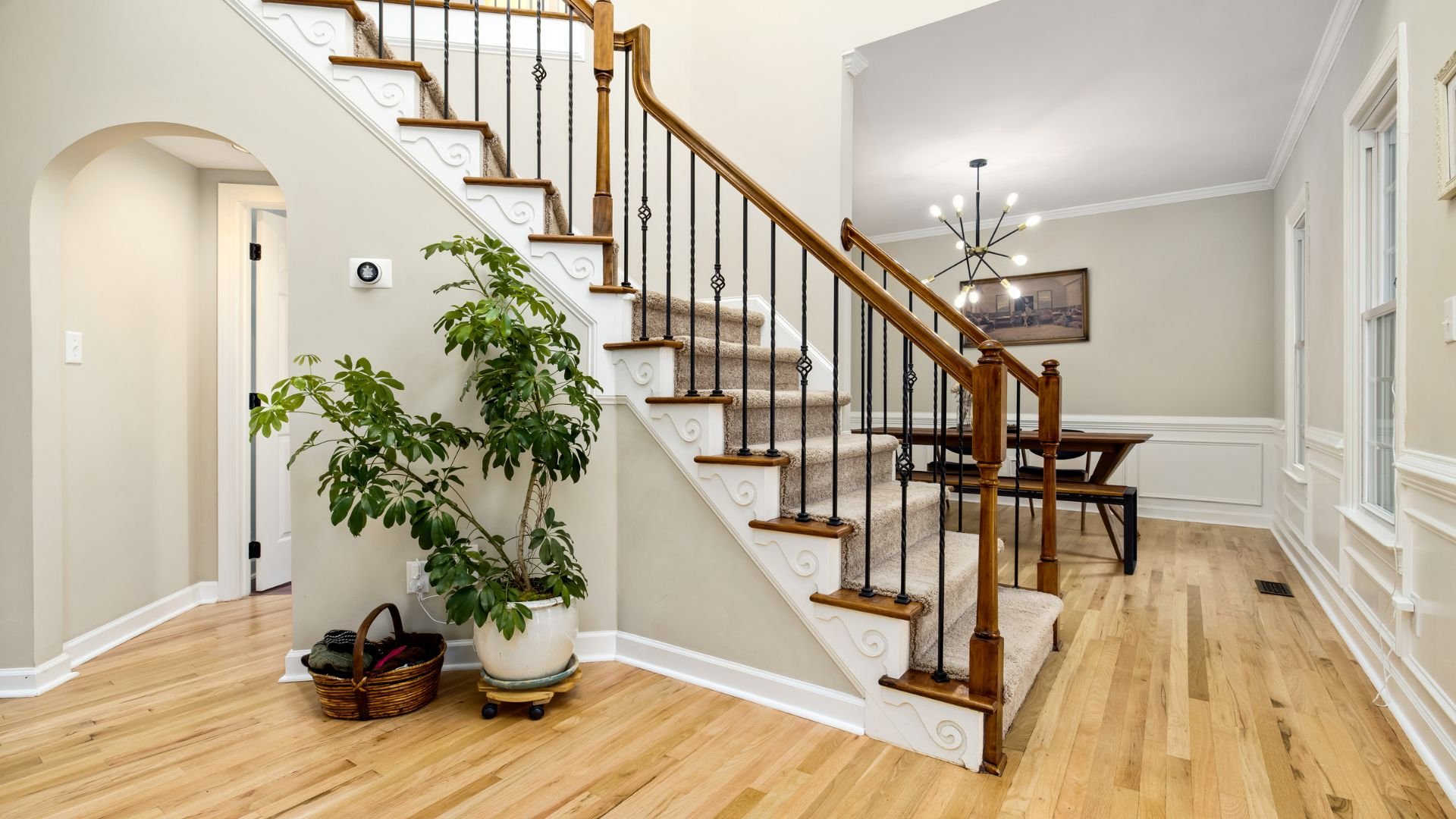 Elegant interior with wooden stairs, potted plant, and hardwood floor
