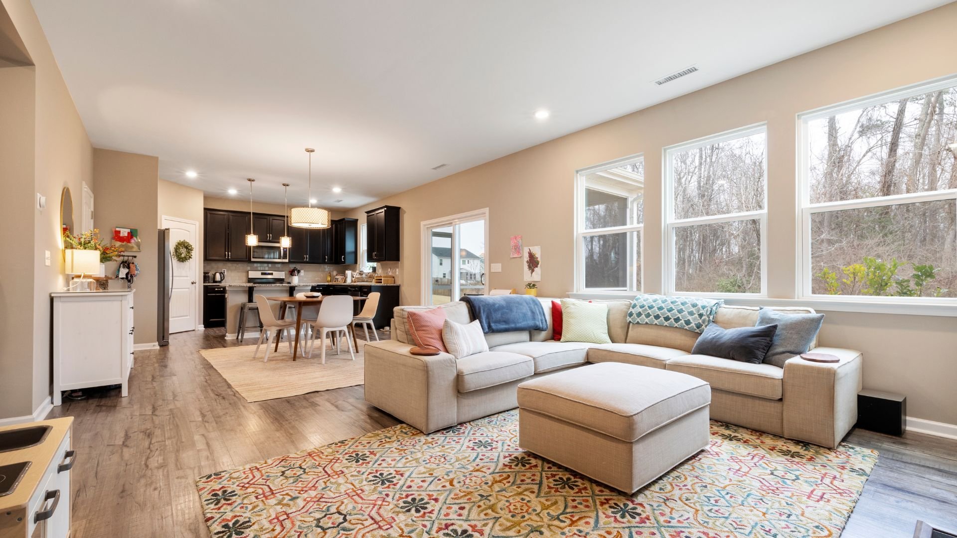 Modern open-concept living room and kitchen with large windows and colorful decor