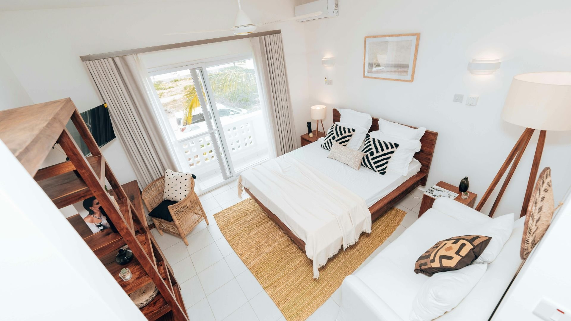 Bright, modern bedroom with wooden furniture and palm tree view